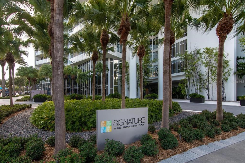 A sign for Signature Place Tower Lofts Plaza stands in front of a modern building — 175 1ST STREET S UNIT 504, ST PETERSBURG, FL