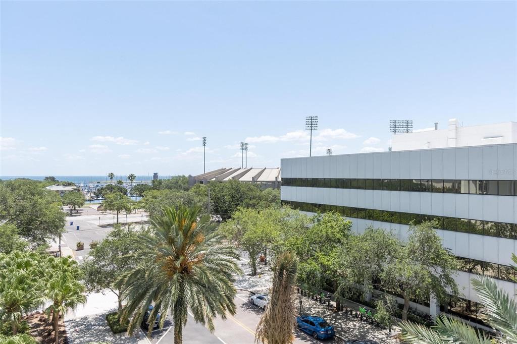An elevated view of a parking lot, palm trees, a modern office building, and water — 175 1ST STREET S UNIT 504, ST PETERSBURG, FL