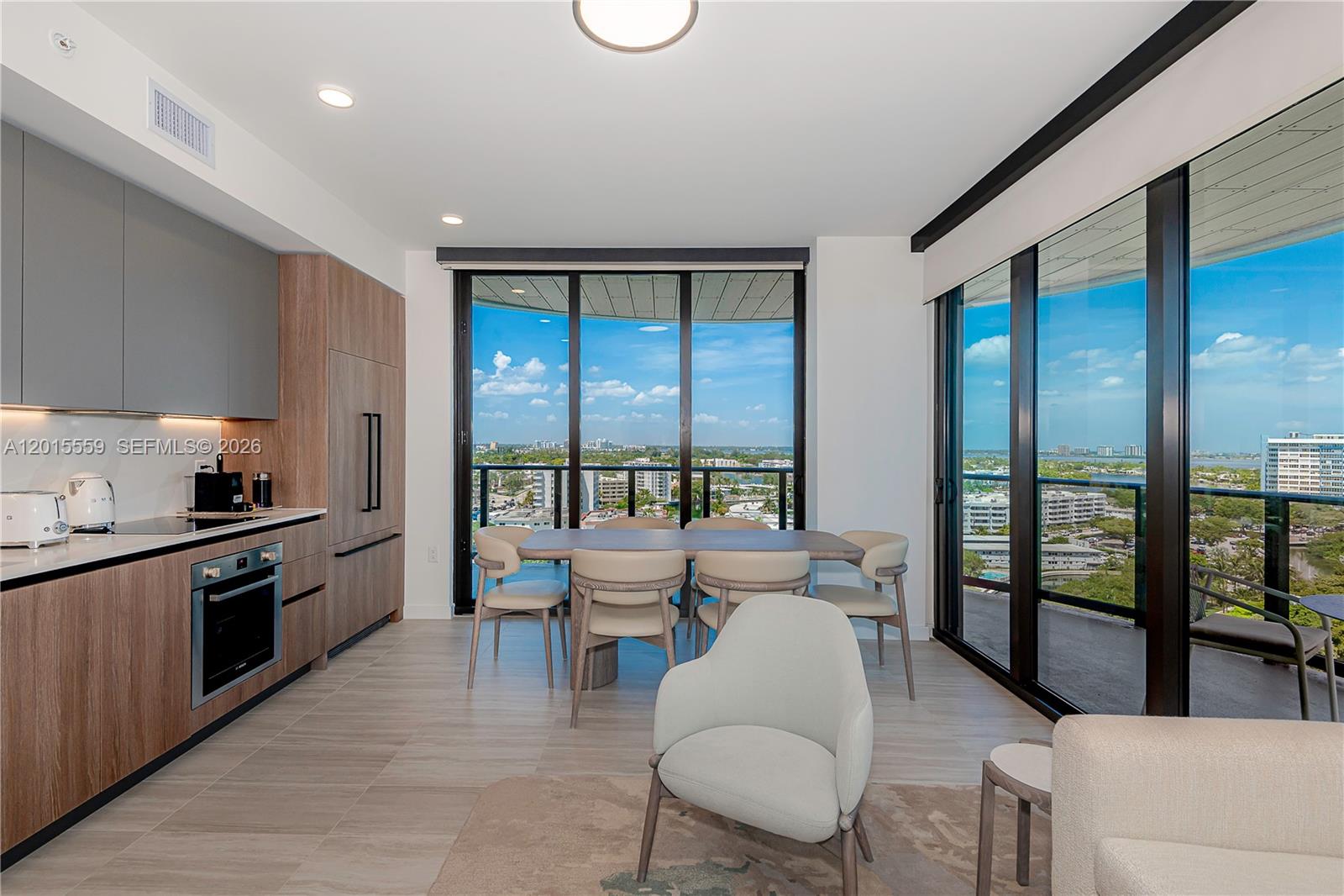 A modern kitchen and dining area feature floor-to-ceiling windows with expansive city and water views — 580 72nd St # 1112, Miami Beach FL 33141, MIAMI BEACH, FL