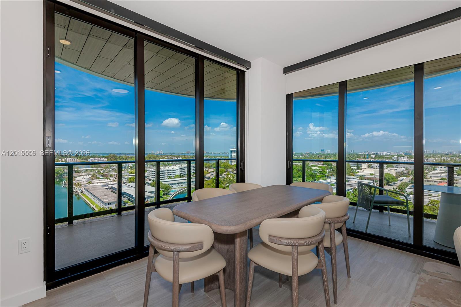 A dining room features a wooden table, six chairs, and floor-to-ceiling windows with balcony access — 580 72nd St # 1112, Miami Beach FL 33141, MIAMI BEACH, FL