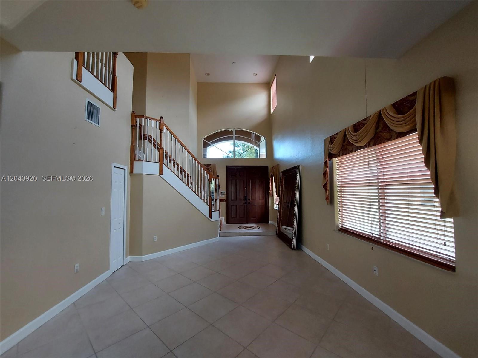 A high-ceilinged foyer features tile flooring, a wooden staircase, and a large arched window — 5350 SW 130th Ter # 5350, Miramar FL 33027, MIRAMAR, FL