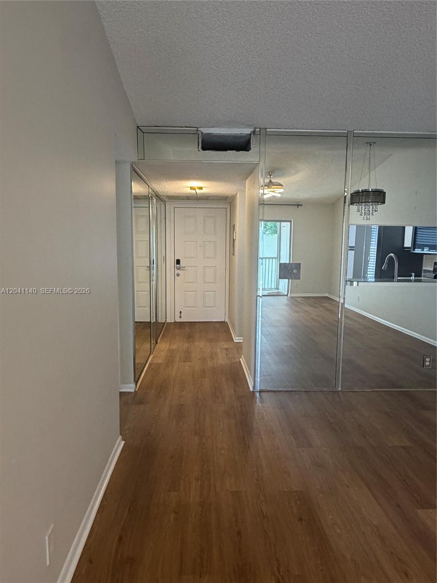 An entryway with wood-look flooring leads to a front door and a mirrored wall — 3031 Holiday Springs Blvd # 7, Margate FL 33063, MARGATE, FL