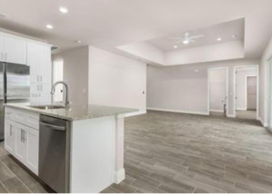 A kitchen island with a stainless steel dishwasher faces an open living area with tile floors — 321 Neighborly Road, FL 33935, FL