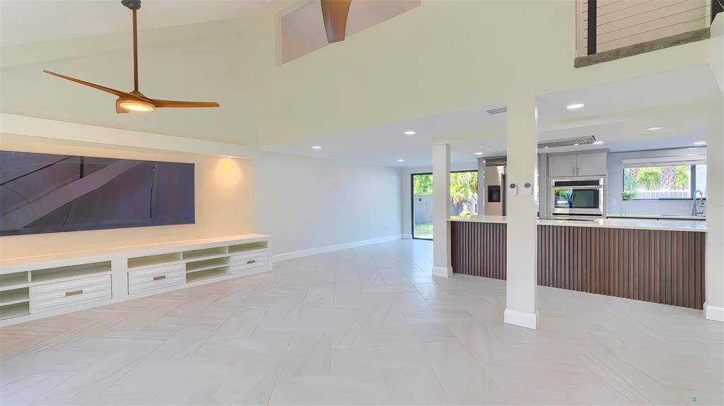An open-concept living area features light-colored tile floors, a built-in media console, and a kitchen — 7331 DIANNE DRIVE, NEW PORT RICHEY, FL