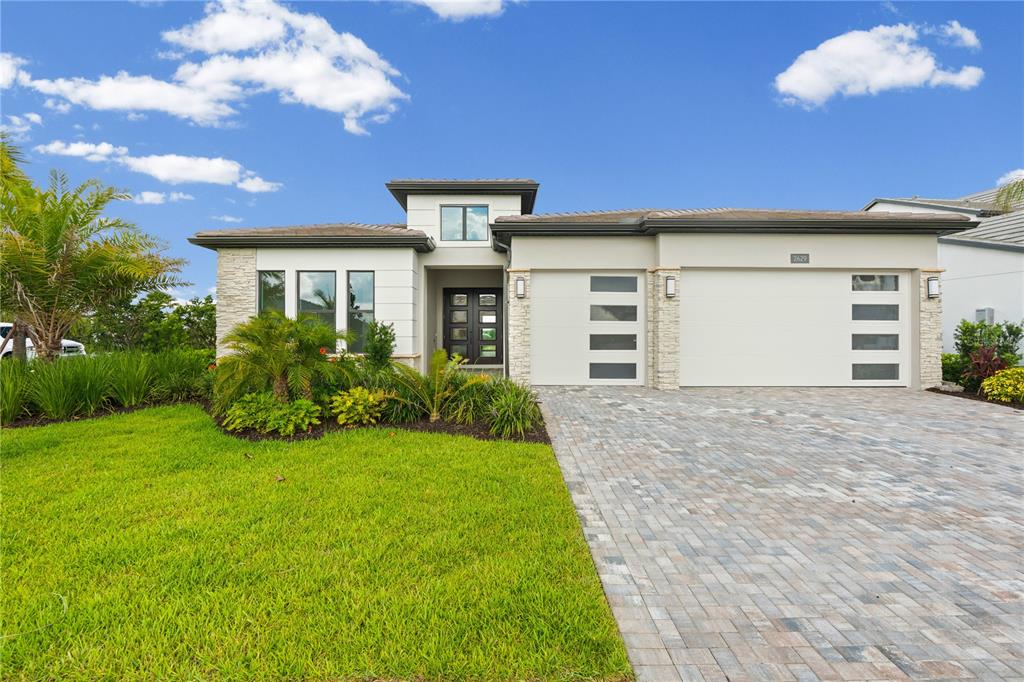 A modern single-story house features a stone-accented facade, a paved driveway, and a three-car garage — 2629 WATERFRONT CIRCLE, SARASOTA, FL