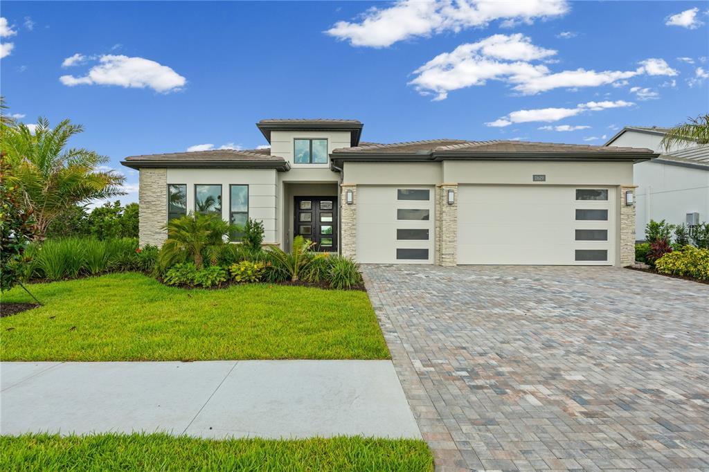 A modern single-story house with a stone-accented facade, a paved driveway, and a three-car garage — 2629 WATERFRONT CIRCLE, SARASOTA, FL
