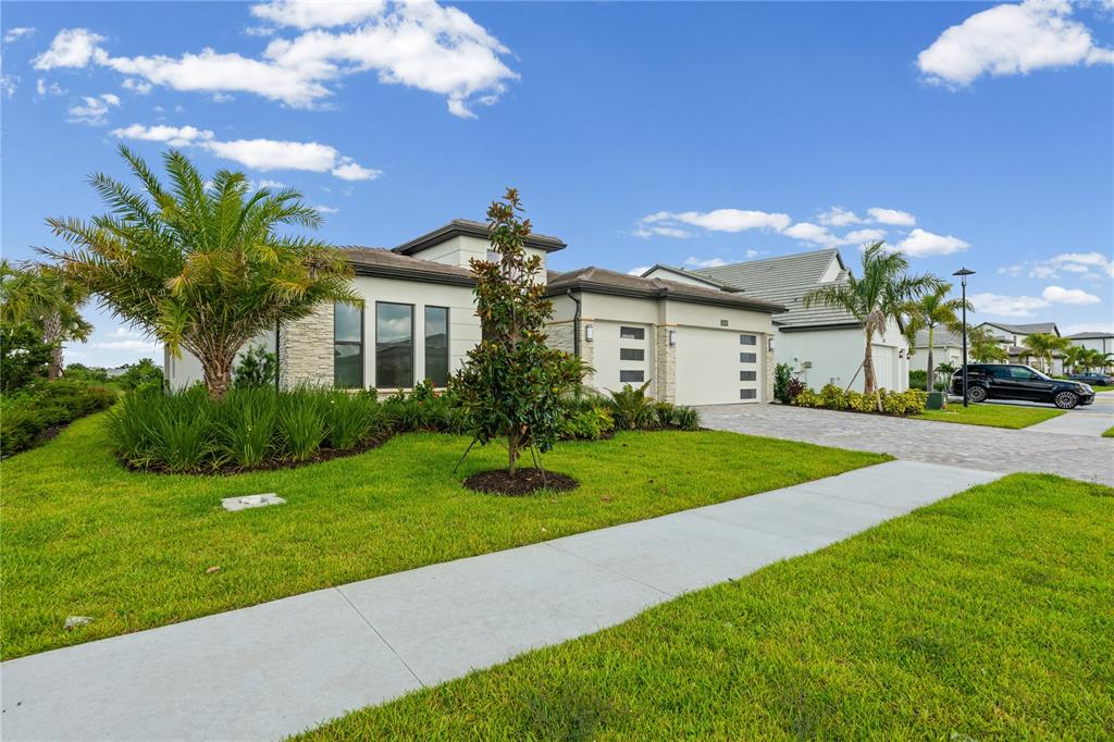 A single-story house with a stone facade, a paved driveway, and a manicured lawn — 2629 WATERFRONT CIRCLE, SARASOTA, FL