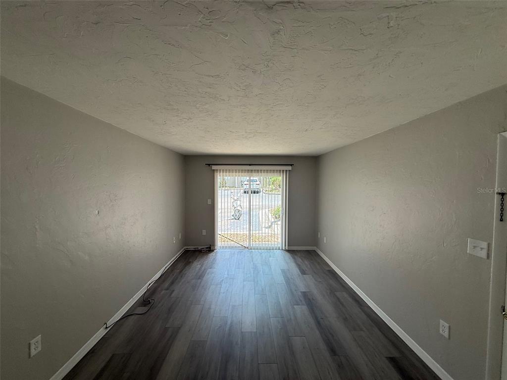 An empty room with gray walls, wood-look flooring, and a sliding glass door — 1035 SW 9TH STREET UNIT 1, GAINESVILLE, FL