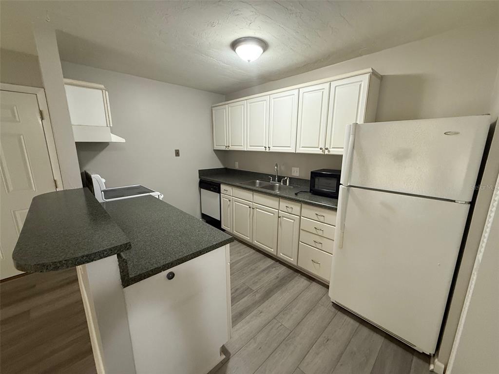 A kitchen features white cabinets, dark countertops, stainless steel appliances, and light wood-look flooring — 1035 SW 9TH STREET UNIT 1, GAINESVILLE, FL