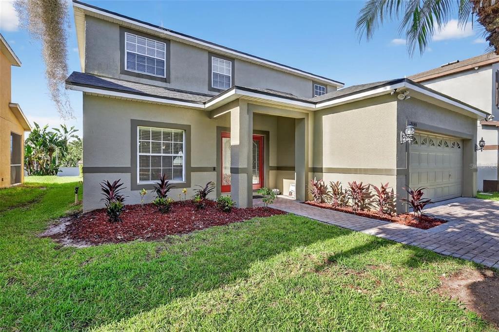 A two-story house with a tan stucco exterior, a red front door, and a garage — 8840 CAMERON CREST DRIVE, TAMPA, FL