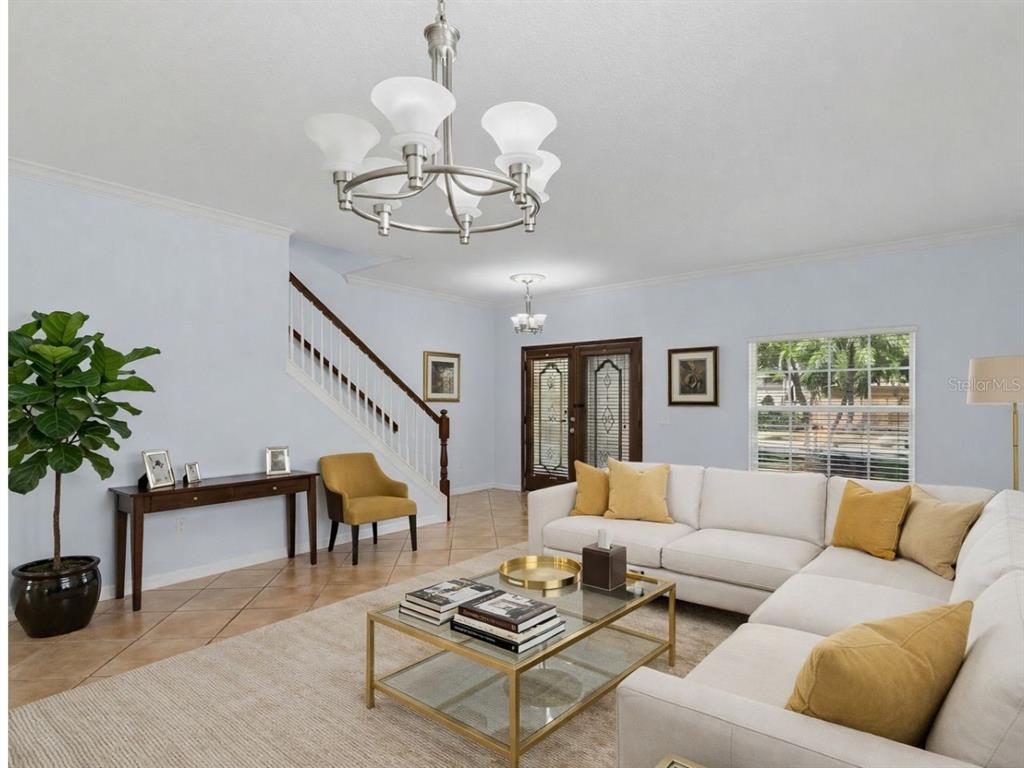 A living room with a white sectional sofa, glass coffee table, and a staircase — 8840 CAMERON CREST DRIVE, TAMPA, FL