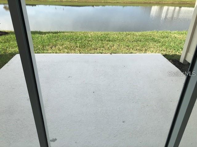 A concrete patio overlooks a grassy lawn and a body of water — 2313 ALEE LANE, WESLEY CHAPEL, FL