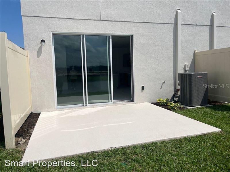 A concrete patio sits outside a sliding glass door next to an air conditioning unit — 2313 ALEE LANE, WESLEY CHAPEL, FL