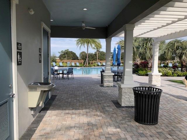 A covered patio with stone columns, a water fountain, and a trash can overlooks a pool — 2313 ALEE LANE, WESLEY CHAPEL, FL