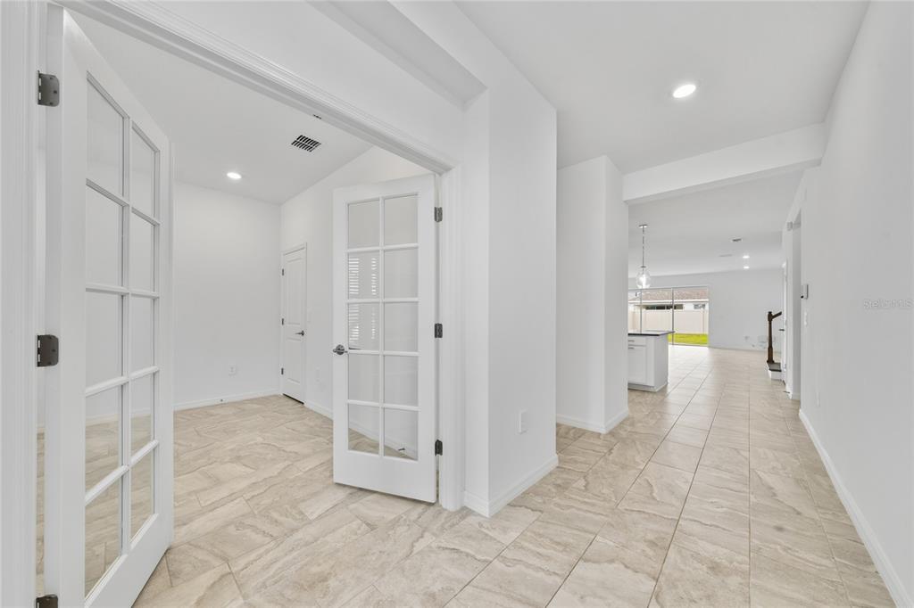 A bright entryway with tile flooring leads to a room with French doors and a hallway — 5237 STONE RIDGE PLACE, ST CLOUD, FL