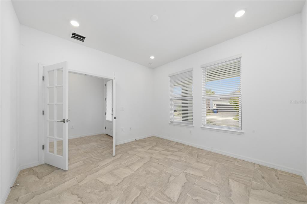 A bright room with white walls, tile flooring, two windows, and French doors — 5237 STONE RIDGE PLACE, ST CLOUD, FL