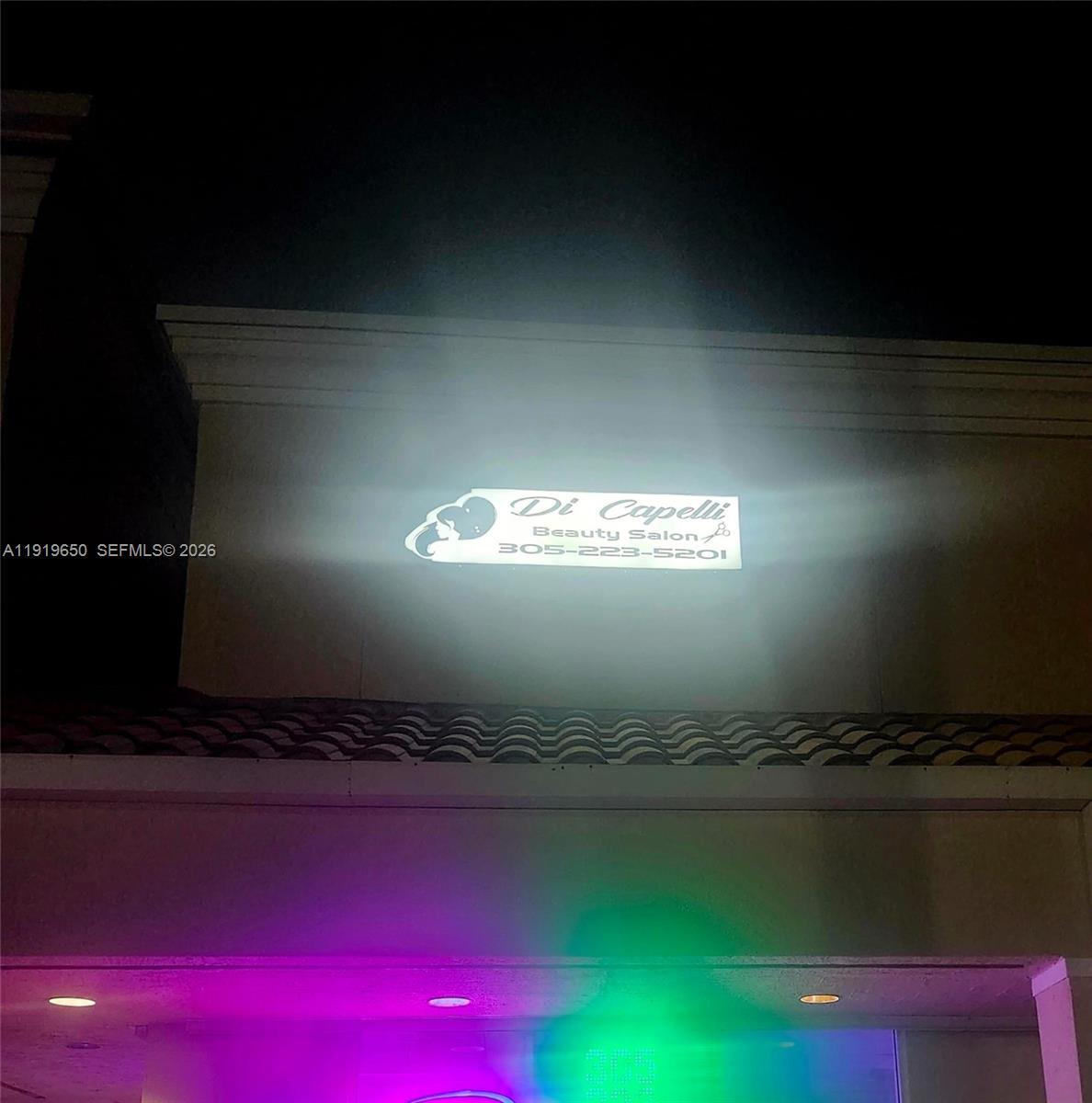 The exterior of a beauty salon at night features a glowing sign with contact information — 14707 SW 42nd St # 401, Miami FL 33185, MIAMI, FL