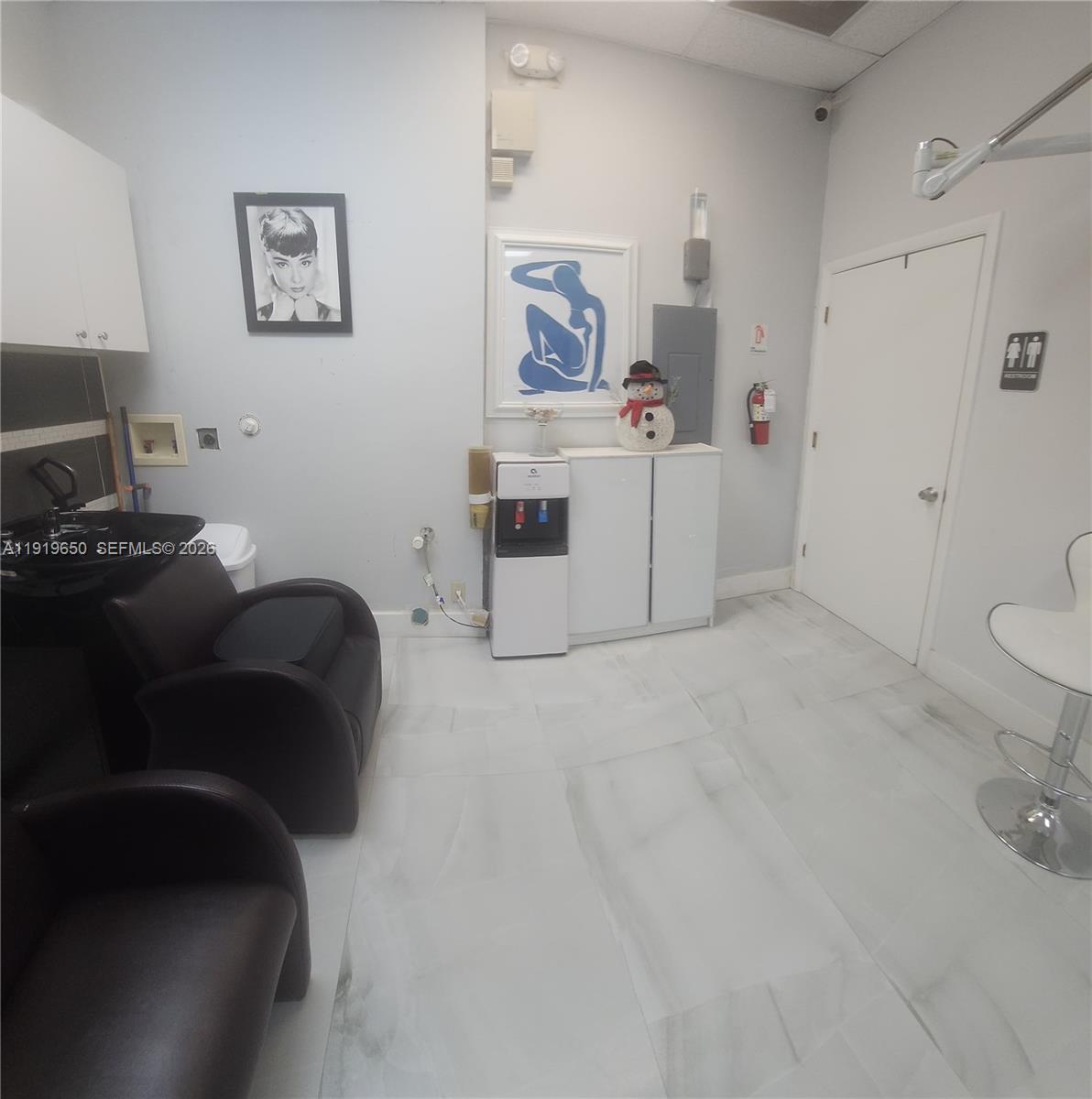 A salon room features two black shampoo chairs, a water cooler, and white tile flooring — 14707 SW 42nd St # 401, Miami FL 33185, MIAMI, FL
