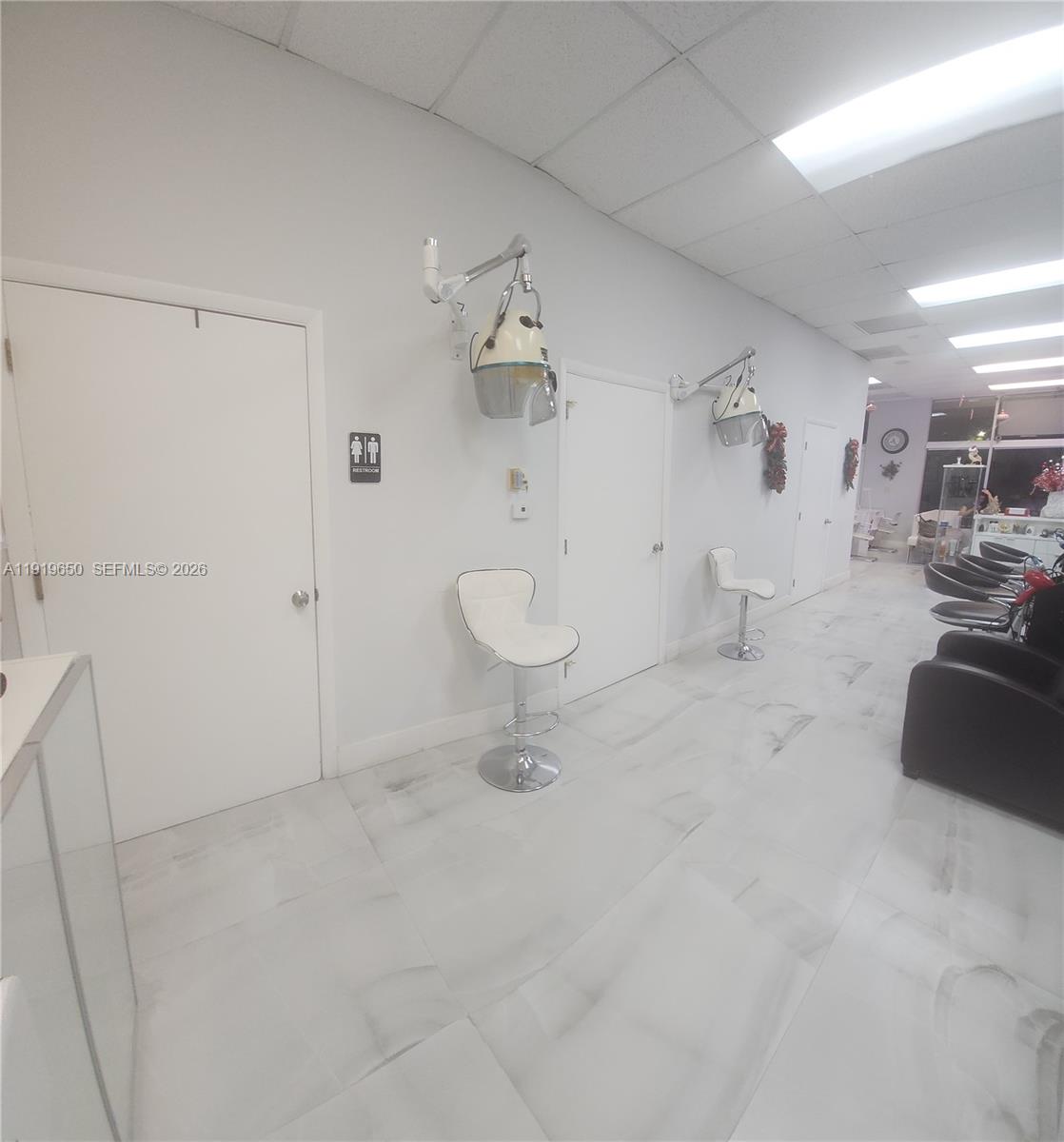 A hair salon interior features white walls, tiled floors, wall-mounted hair dryers, and styling chairs — 14707 SW 42nd St # 401, Miami FL 33185, MIAMI, FL