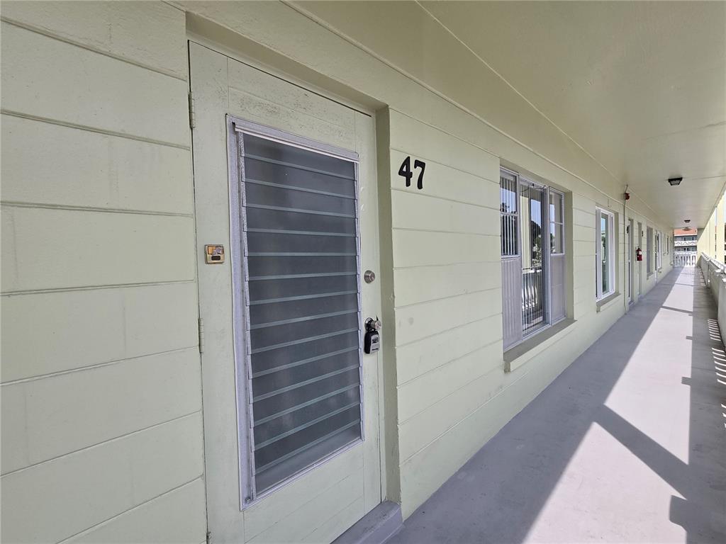 An exterior view of a building hallway showing apartment door number 47 with a louvered door — 2459 COLUMBIA DRIVE UNIT 47, CLEARWATER, FL
