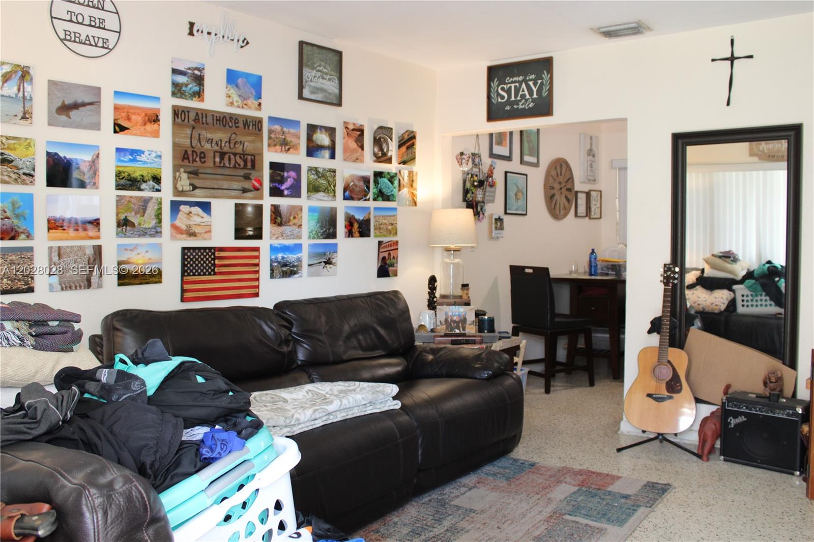 A living room features a black leather sofa, a photo gallery wall, and a guitar — 1022 NW 22nd Pl, Miami FL 33125, MIAMI, FL