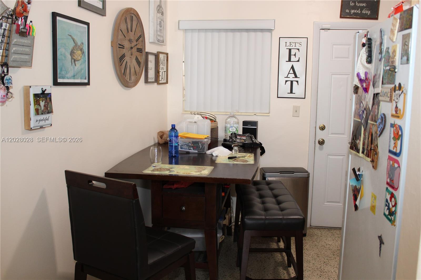 A dining area features a dark wood table, two chairs, a bench, and wall decor — 1022 NW 22nd Pl, Miami FL 33125, MIAMI, FL
