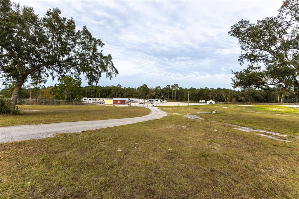 A gravel driveway leads toward a fenced storage lot filled with parked recreational vehicles — 1177 SE KEYSTONE AVENUE, KEYSTONE HEIGHTS, FL