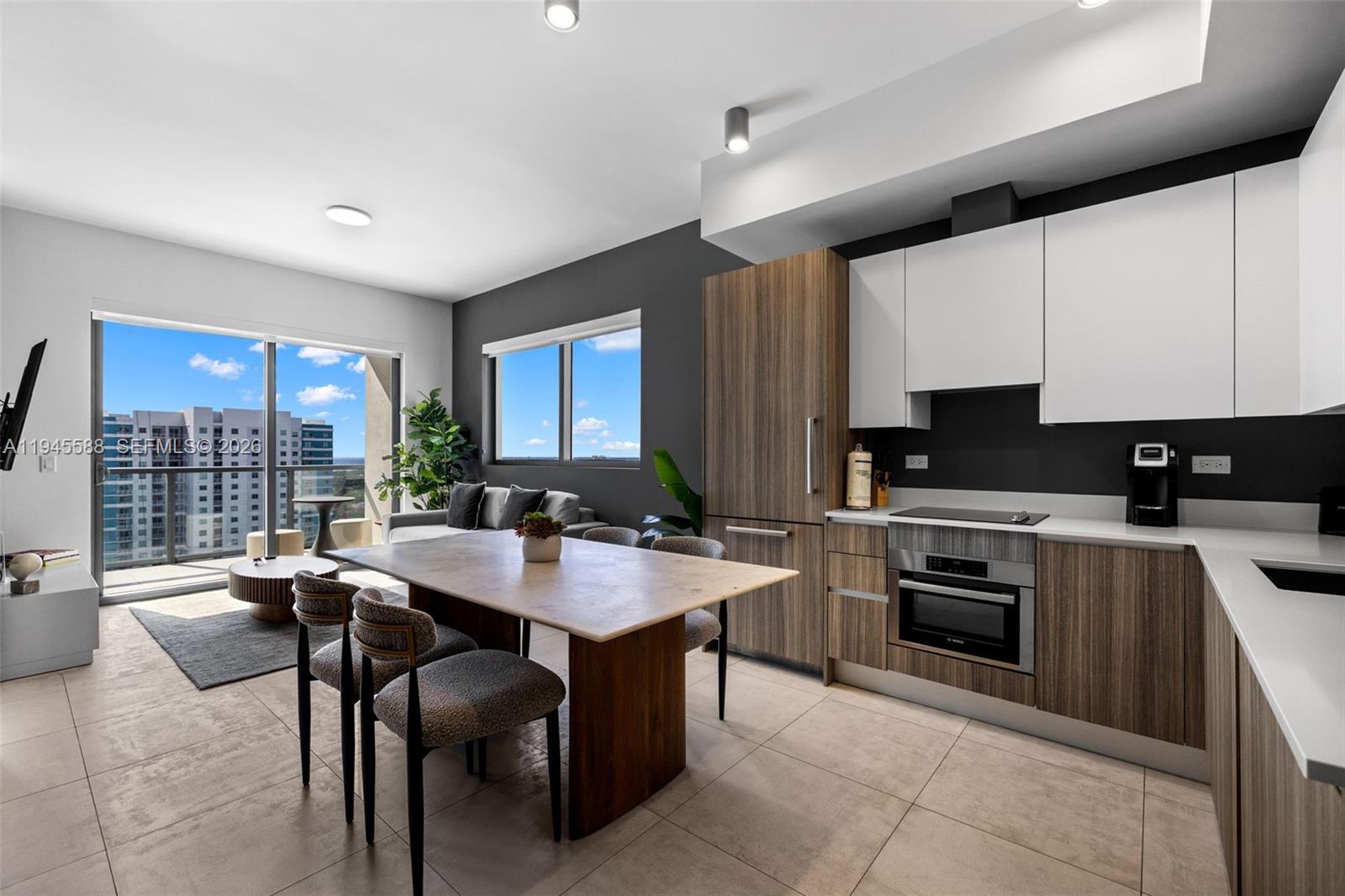 A modern kitchen and dining area features wood-toned cabinetry, white upper cabinets, and tile flooring — 239 SW 9th St # 2102, Miami FL 33130, MIAMI, FL