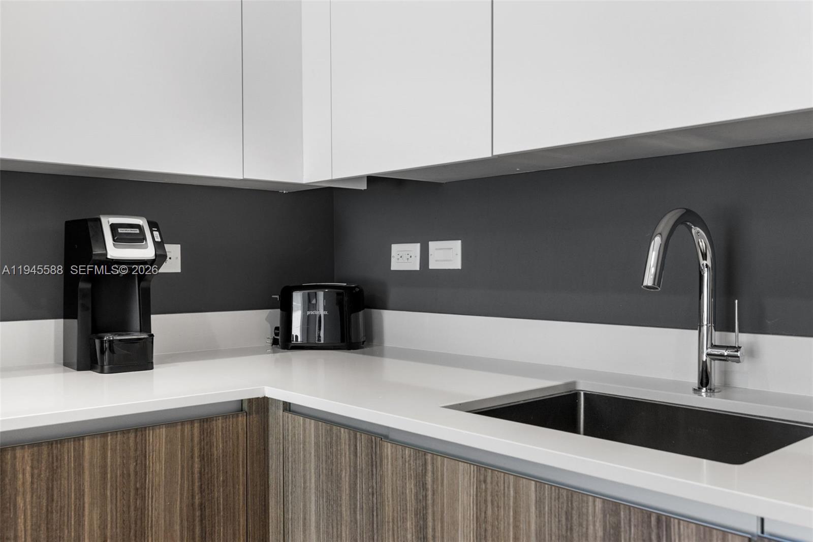 A modern kitchen features white upper cabinets, wood-grain lower cabinets, a dark backsplash, and a sink — 239 SW 9th St # 2102, Miami FL 33130, MIAMI, FL