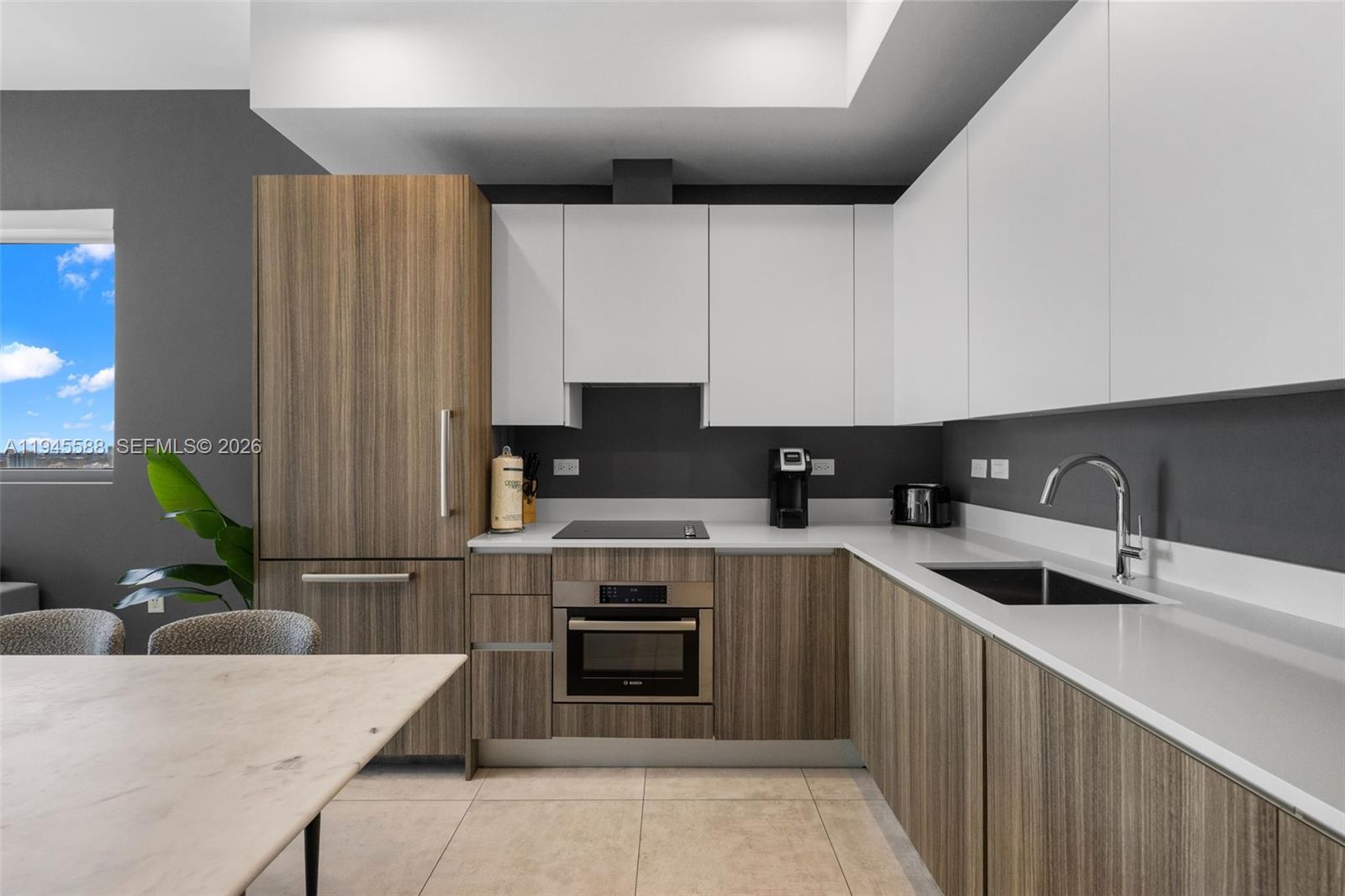 A modern kitchen features wood-grain cabinetry, white upper cabinets, a dark backsplash, and stone countertops — 239 SW 9th St # 2102, Miami FL 33130, MIAMI, FL
