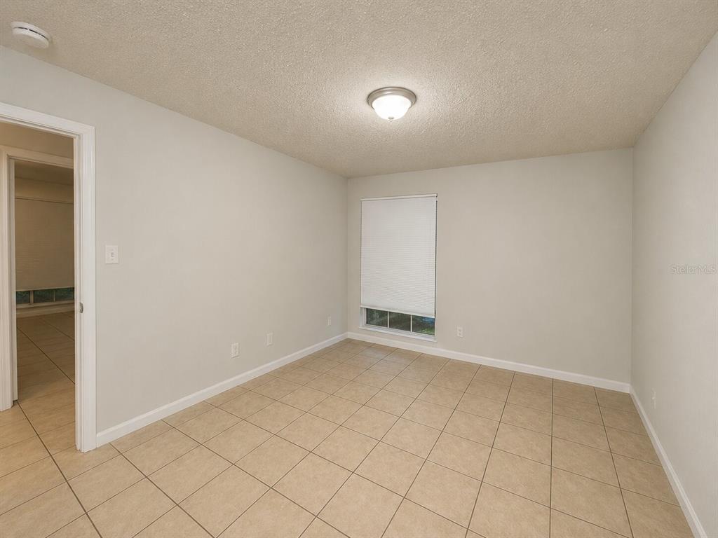 An empty room with light-colored walls, tile flooring, a ceiling light, and a window — 405 WYMORE ROAD UNIT 106, ALTAMONTE SPRINGS, FL