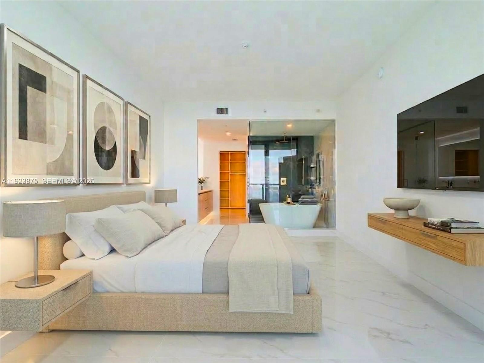 A modern bedroom features a platform bed, marble floors, and an open-concept glass-enclosed bathroom — 700 NE 24 st # 4201, Miami FL 33137, MIAMI, FL