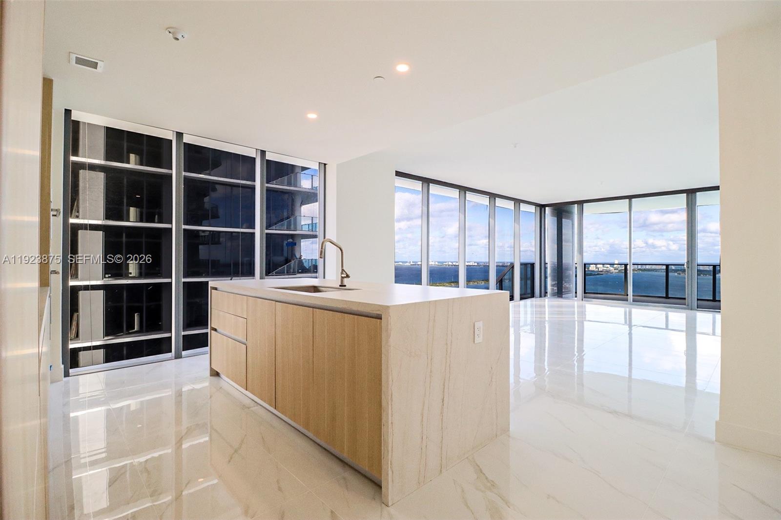 A modern kitchen island with light wood cabinetry sits in a room with floor-to-ceiling windows — 700 NE 24 st # 4201, Miami FL 33137, MIAMI, FL