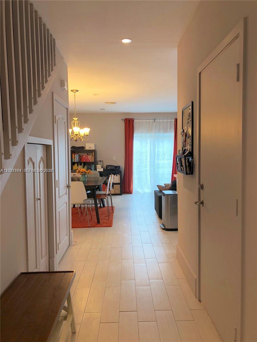 A hallway with light tile flooring leads to a dining area and living space — 33 SE 3rd Ave, Hallandale Beach FL 33009, HALLANDALE BEACH, FL
