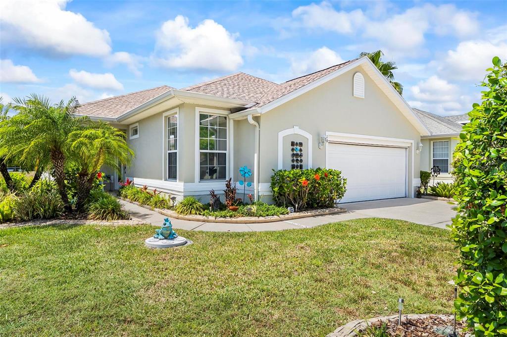 A single-story house with a beige exterior, a two-car garage, and a landscaped front yard — 19 RAINTREE CIRCLE, PALM COAST, FL