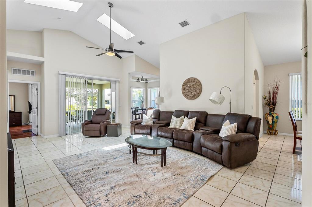 A living room with tile floors, a large brown sectional, and a vaulted ceiling — 19 RAINTREE CIRCLE, PALM COAST, FL