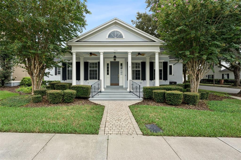 A light blue single-story house with a front porch, columns, and a brick walkway — 906 SPRING PARK LOOP, CELEBRATION, FL