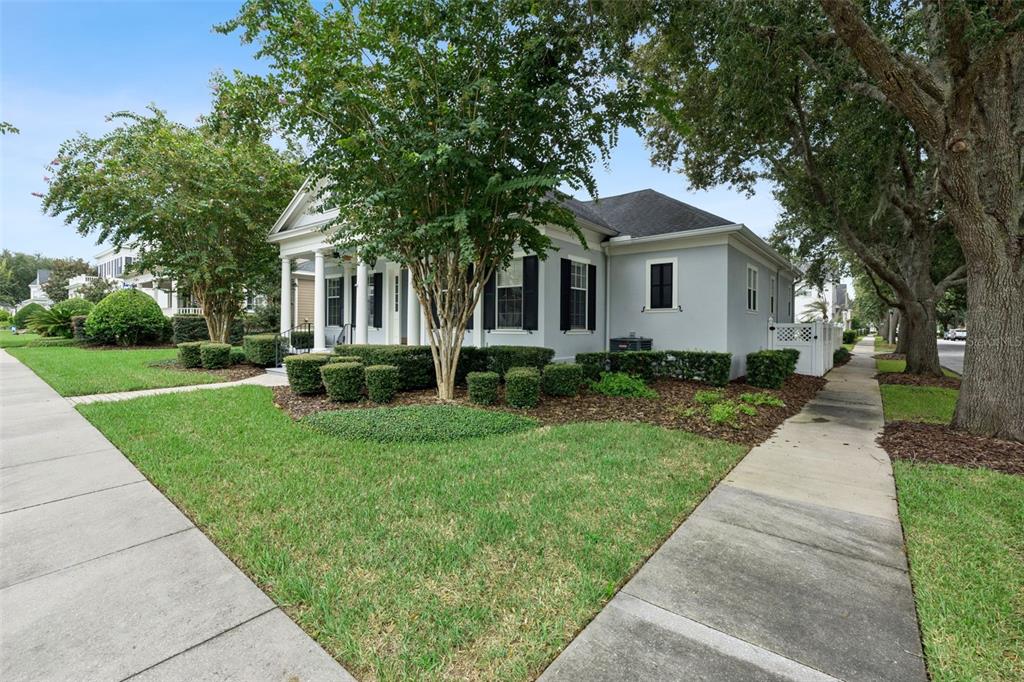 A light gray house with black shutters and a front porch sits on a corner lot — 906 SPRING PARK LOOP, CELEBRATION, FL