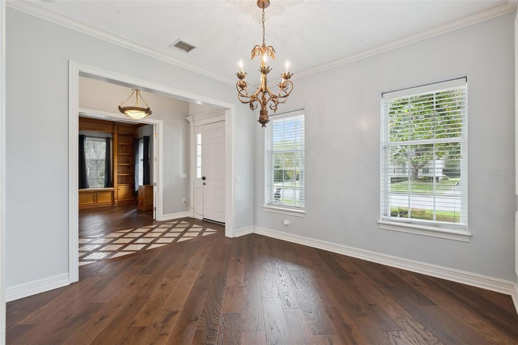 A dining room with dark wood floors, a chandelier, and a view into a study — 906 SPRING PARK LOOP, CELEBRATION, FL