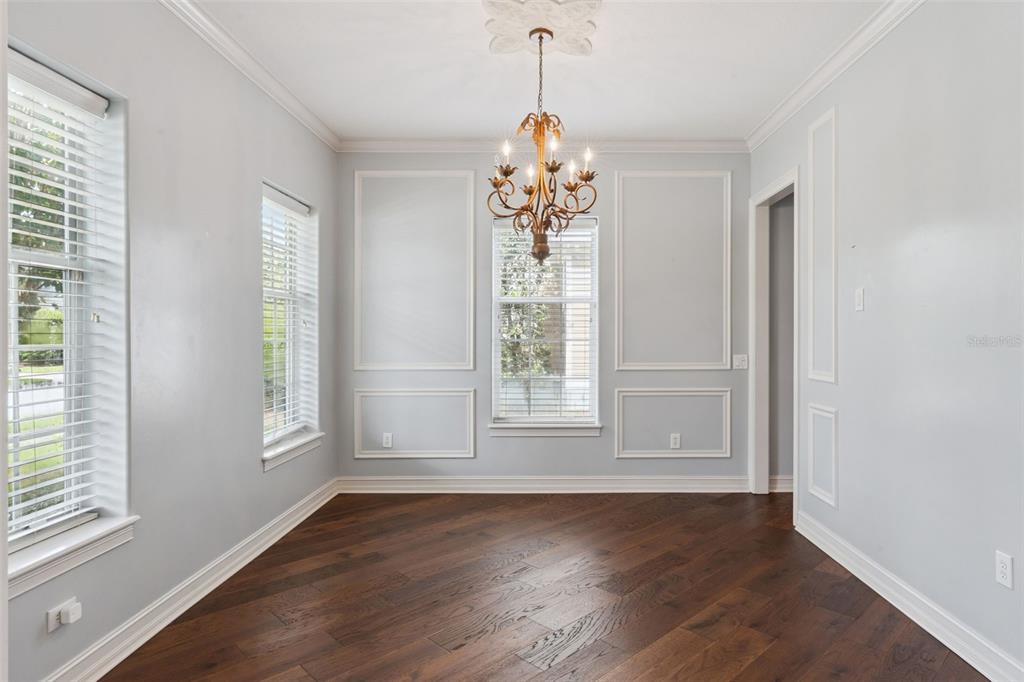 A dining room with light blue walls, white wainscoting, a chandelier, and dark wood flooring — 906 SPRING PARK LOOP, CELEBRATION, FL