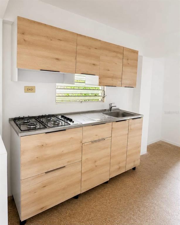 A kitchen features light wood-grain cabinets, a stainless steel countertop, a gas cooktop, and sink — PR-2 Km 90.2 BO PUENTE, CAMUY, PR