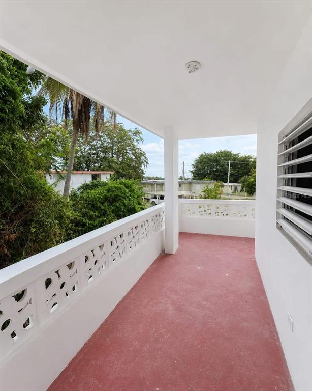 A covered balcony features a red floor, white decorative concrete railings, and a white ceiling — PR-2 Km 90.2 BO PUENTE, CAMUY, PR