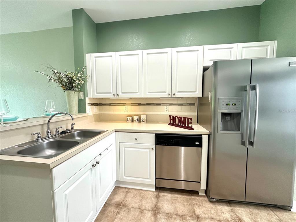 A kitchen features white cabinets, stainless steel appliances, a double sink, and light countertops — 11096 WINTER CREST DRIVE, RIVERVIEW, FL