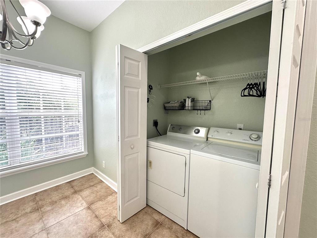 A laundry room features a white washer and dryer set inside a closet with shelving — 11096 WINTER CREST DRIVE, RIVERVIEW, FL