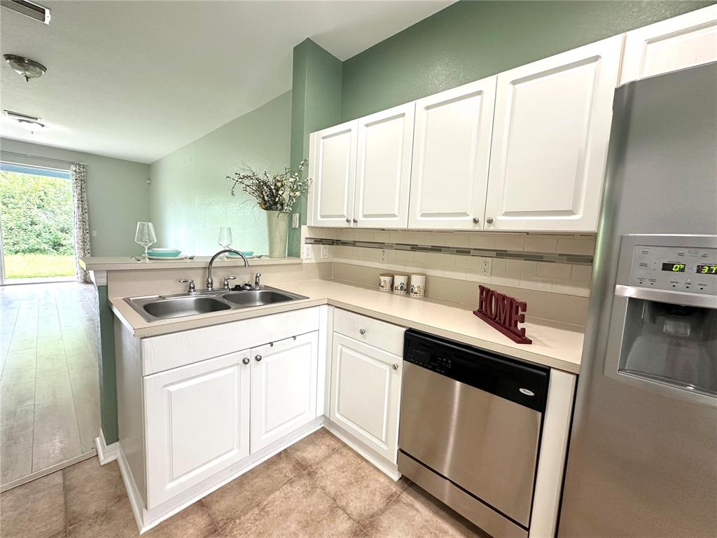 A kitchen features white cabinets, stainless steel appliances, a double sink, and light countertops — 11096 WINTER CREST DRIVE, RIVERVIEW, FL