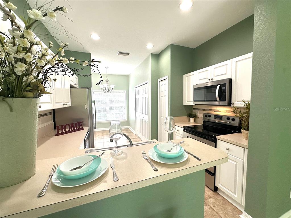 A kitchen features white cabinets, a stainless steel microwave, and a breakfast bar with place settings — 11096 WINTER CREST DRIVE, RIVERVIEW, FL