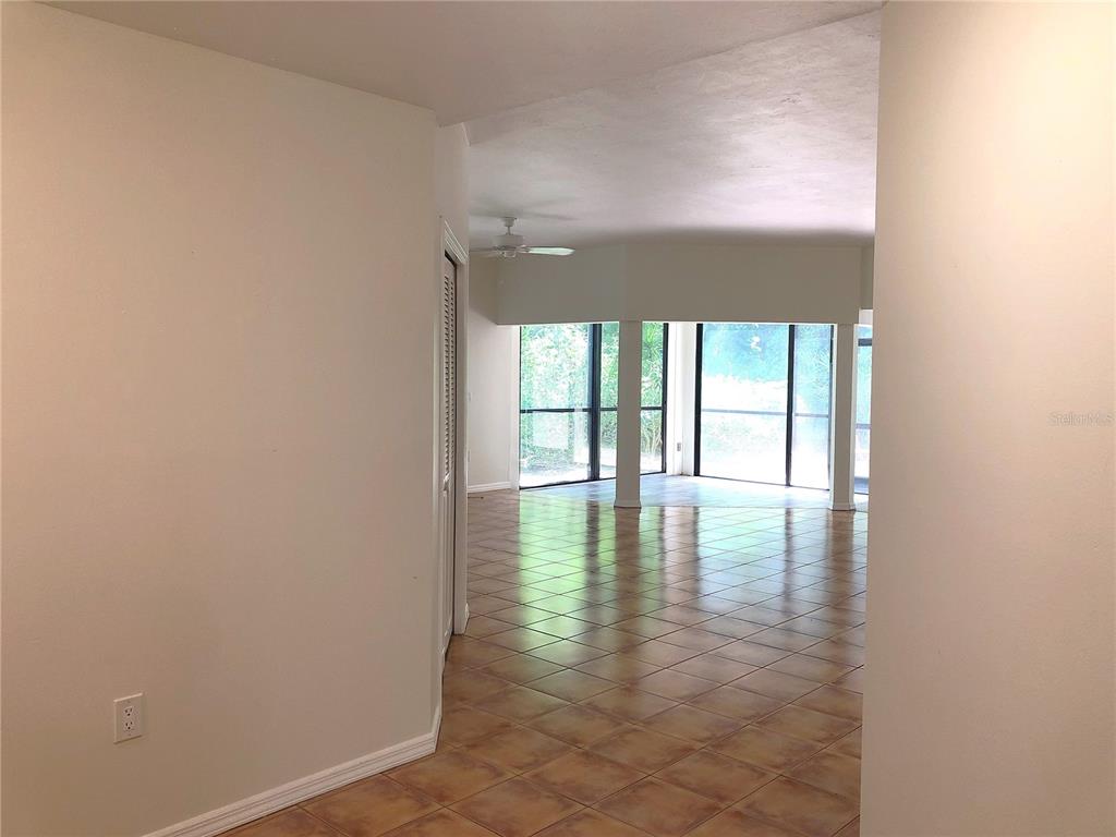 A view from a hallway into a living area with tiled floors and large windows — 1664 STARLING DRIVE UNIT 101, SARASOTA, FL
