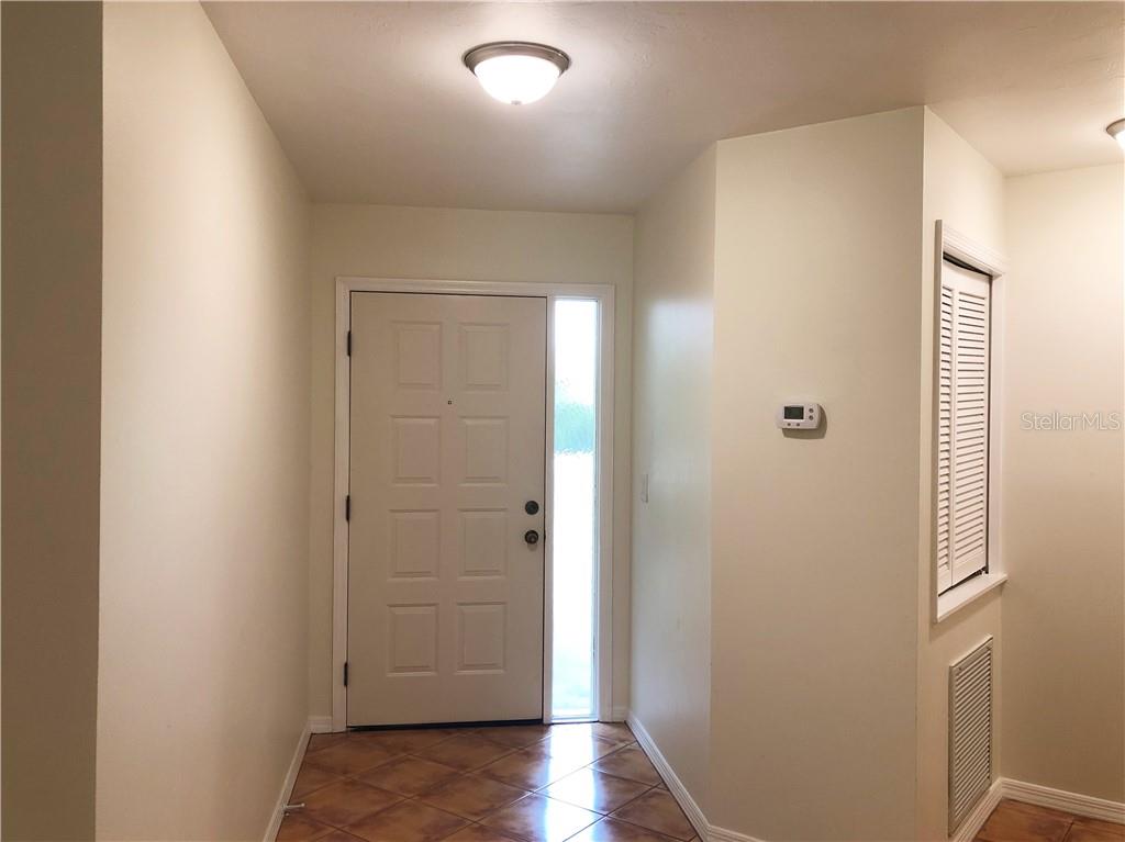 An entryway features a white front door with a sidelight, tile flooring, and a thermostat — 1664 STARLING DRIVE UNIT 101, SARASOTA, FL