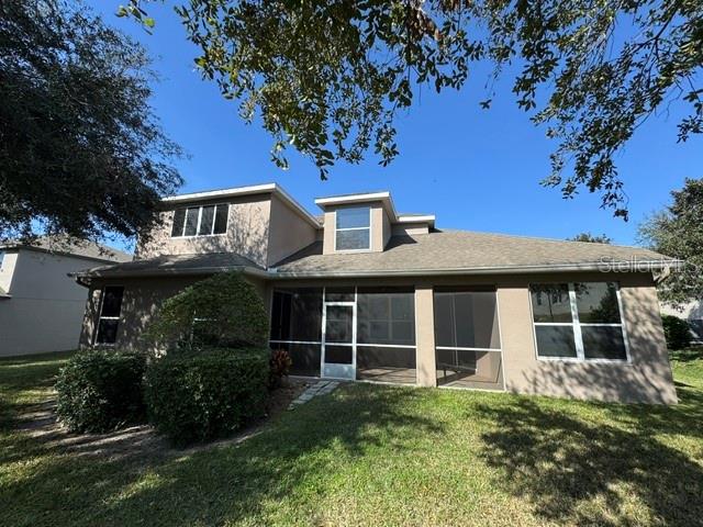 The rear exterior of a two-story house features a screened-in patio and a grassy yard — 1079 GLENRAVEN LANE, CLERMONT, FL