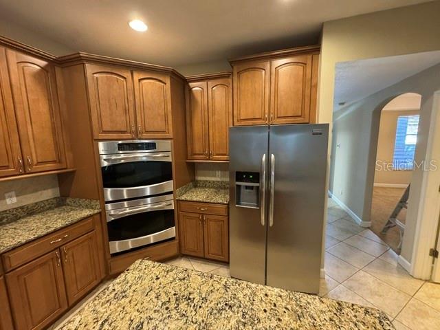 A kitchen features wood cabinets, granite countertops, a double wall oven, and a stainless refrigerator — 1079 GLENRAVEN LANE, CLERMONT, FL